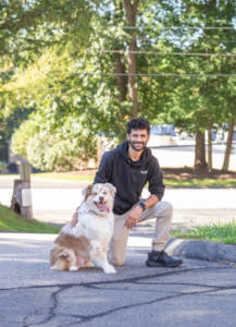 Ivan Rios kneeling next to an Australian Shepherd
